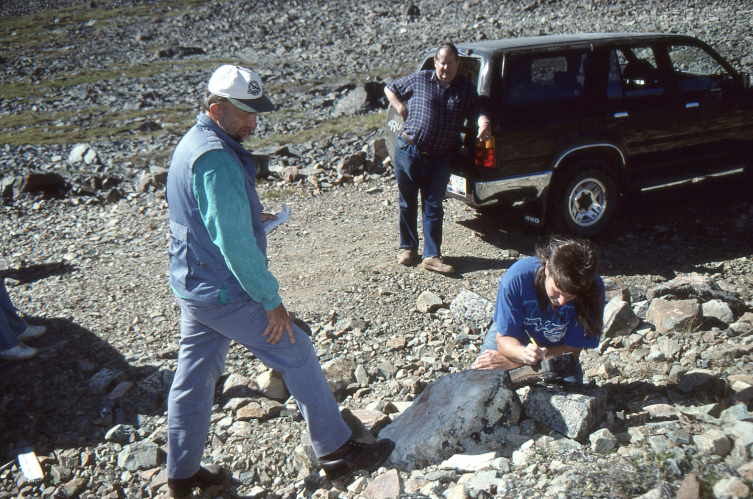John Phelps Jr. writes out his claim post tag while Willard Phelps and John Phelps Sr. look on.
